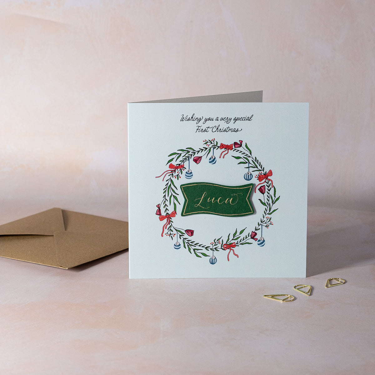 Christmas card with wreath design and personalised calligraphy name. Boy first Christmas.