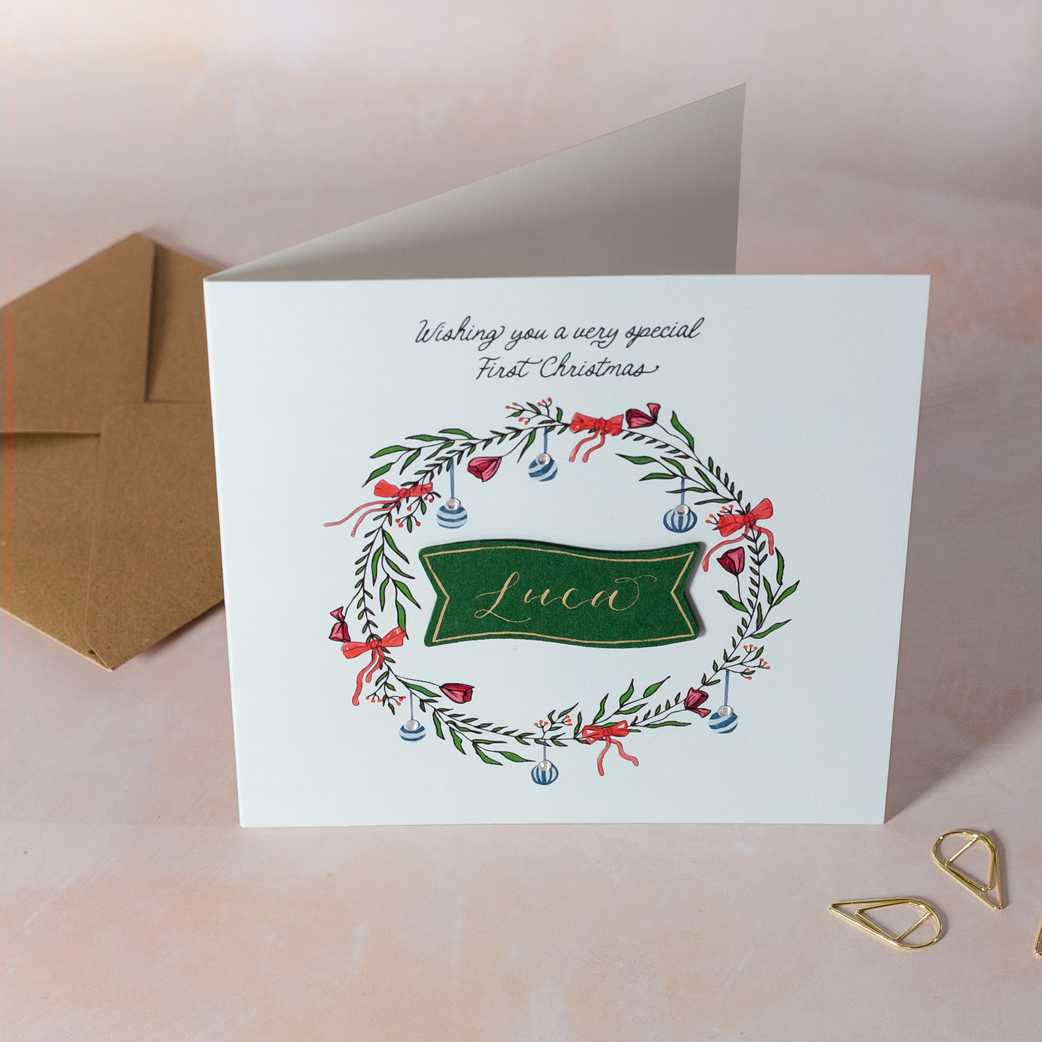 Personalised wreath Christmas card on blue background for boy's first Christmas.