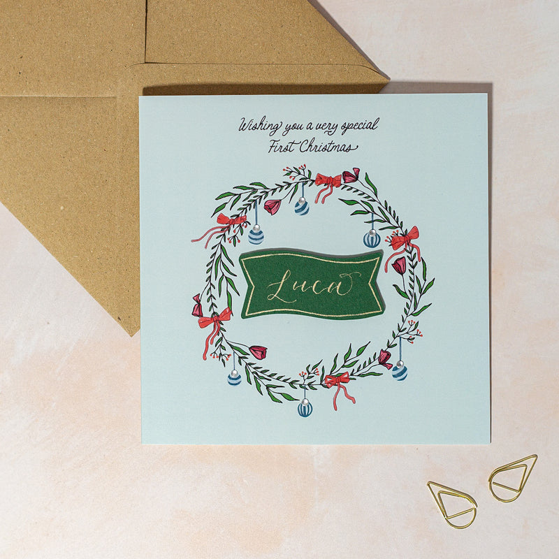 Personalised greeting card with festive wreath design for baby boy's first Christmas.