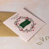 Christmas card for baby girl 1st Christmas with decorative wreath and handwritten calligraphy name.