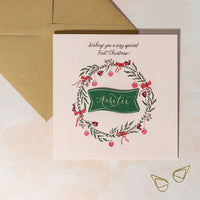 Christmas card for baby girl's first Christmas. Wreath design with personalised name.