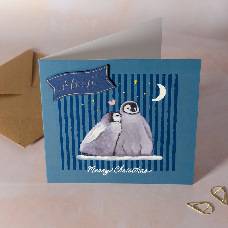 Personalised Christmas card with penguin under starry sky and 'Merry Christmas' text on a blue background