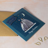 Christmas card with penguin illustration and 'Merry Christmas' text on a blue background.