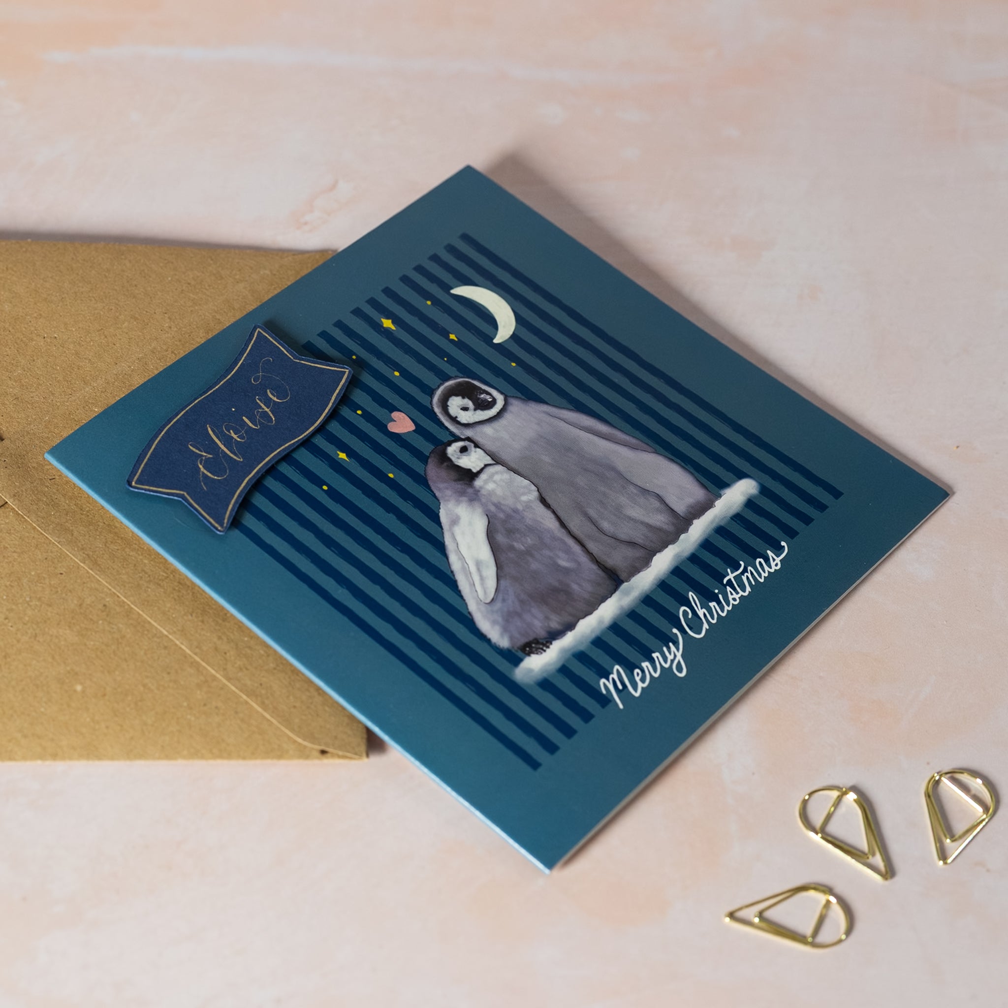 Christmas card with penguin illustration and 'Merry Christmas' text on a blue background.