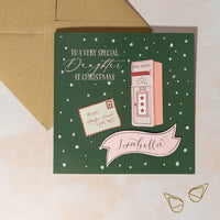 Personalised Christmas card with a pink mailbox illustration on a green background with snow in background and handwritten calligraphy name