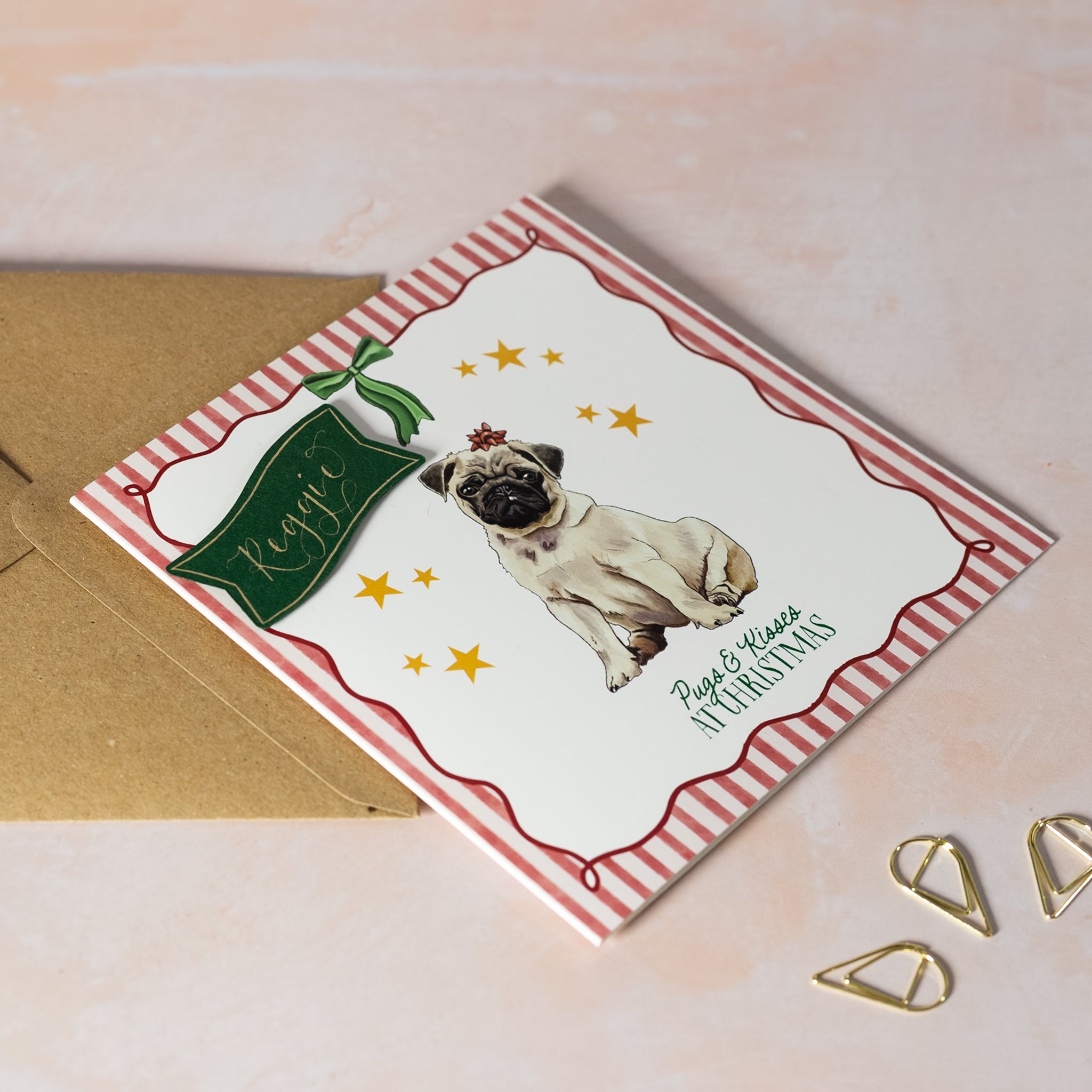 Christmas card with a pug illustration and text 'Pugs & kisses at Christmas'. Personalised calligraphy name.