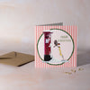 Christmas card with a red postbox and festive design on a pink striped background
