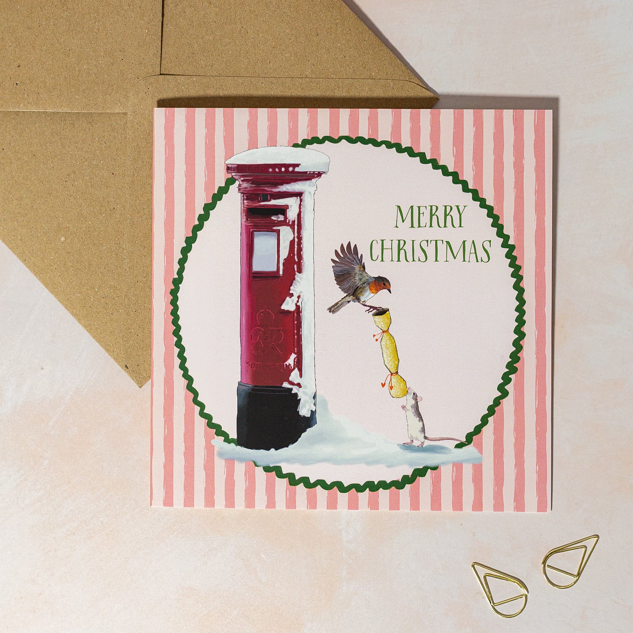 Christmas card with a red postbox, robin, and mouse on a striped pink background