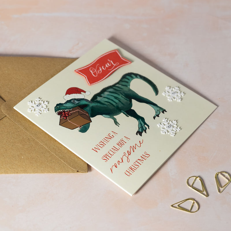 Christmas card with a dinosaur wearing a Christmas hat, eating a gift. Perfect for dino-lovers.