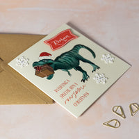 Christmas card with a dinosaur holding a gift, personalised name on red card.
