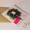 Pink Christmas card with wreath design and personalised calligraphy name.