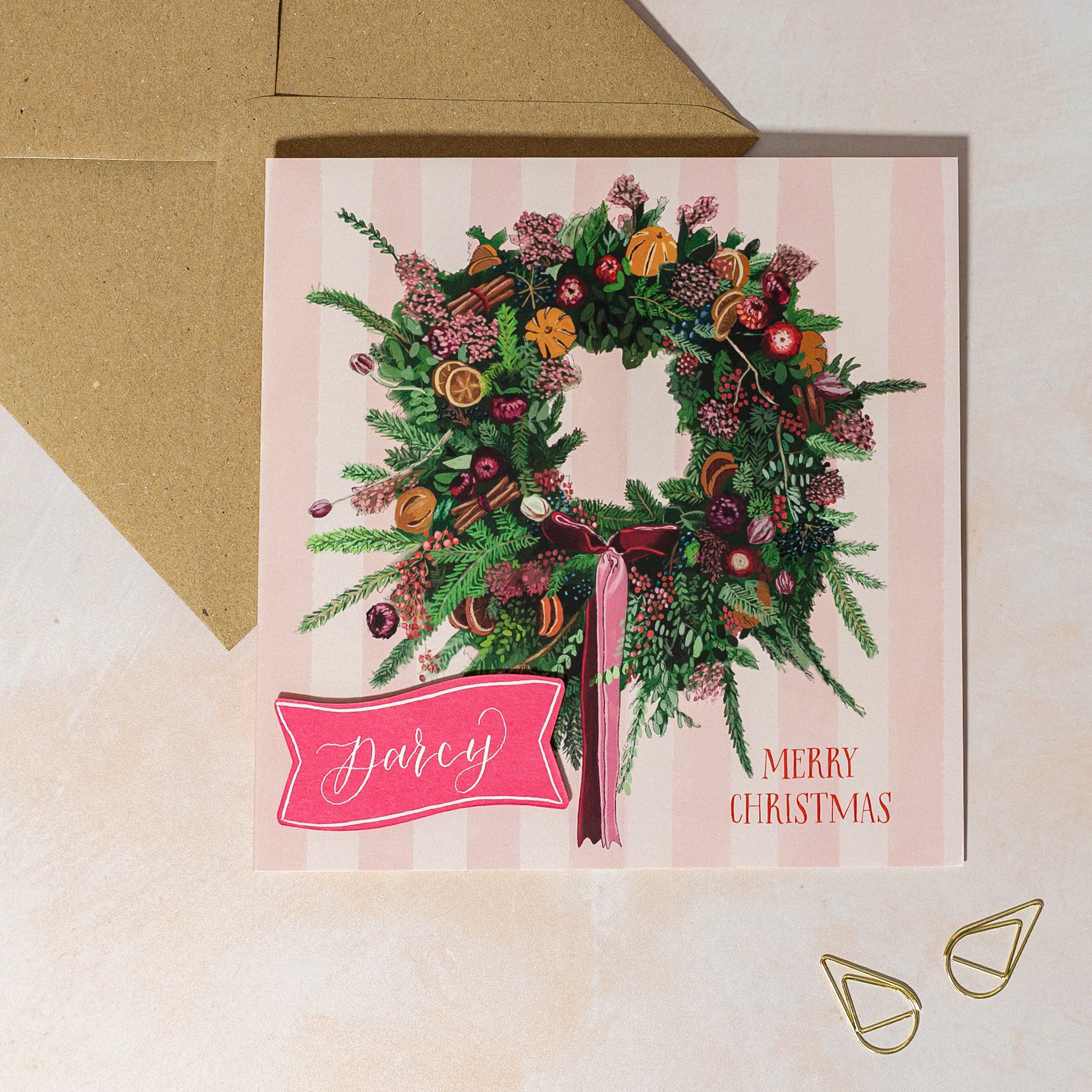 Personalised Christmas card with a wreath design and 'Merry Christmas' text on a striped background.
