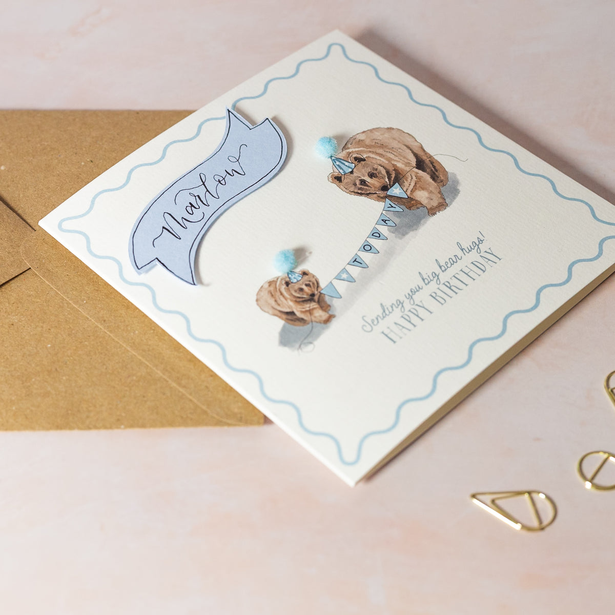 Birthday card with bear design and envelope on a light pink background