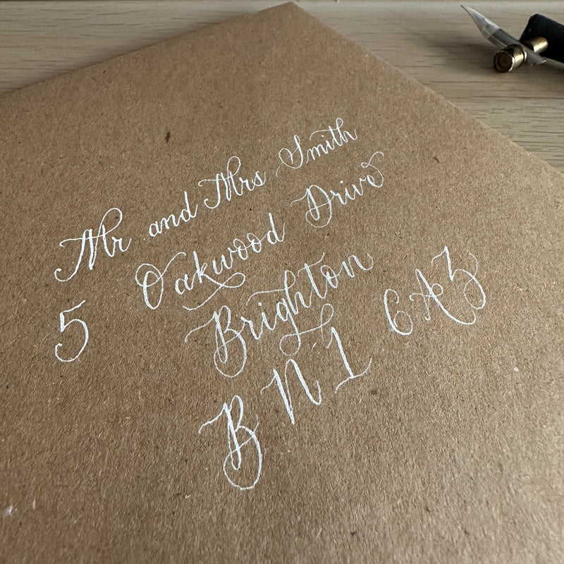 Brown envelope addressed in modern calligraphy style, white ink